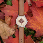 Watch with a maple leaf design on a bed of autumn maple leaves