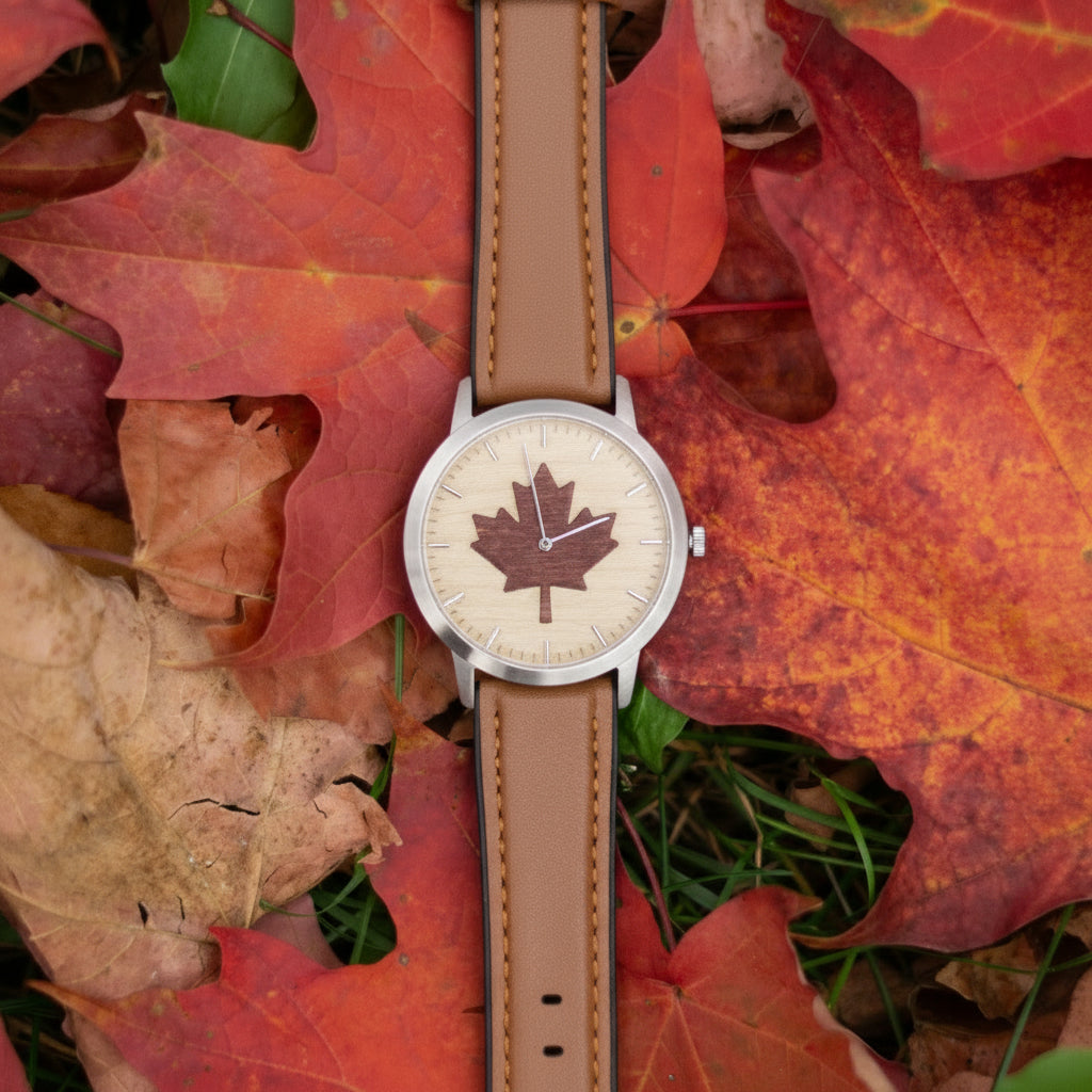Watch with a maple leaf design on a bed of autumn maple leaves